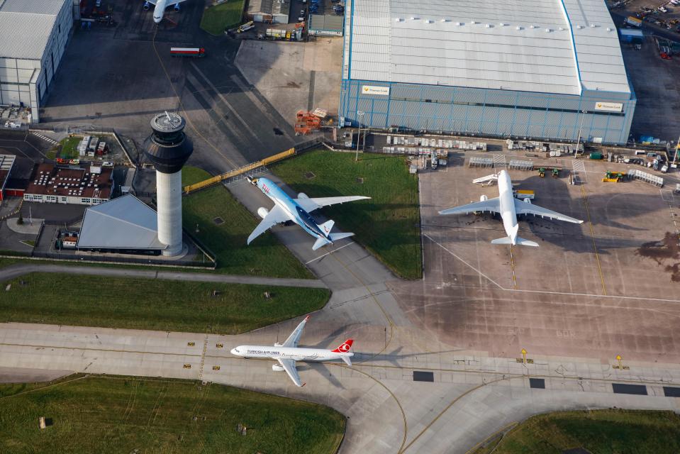 Aerial view of Manchester Airport with three airplanes and air traffic control tower.