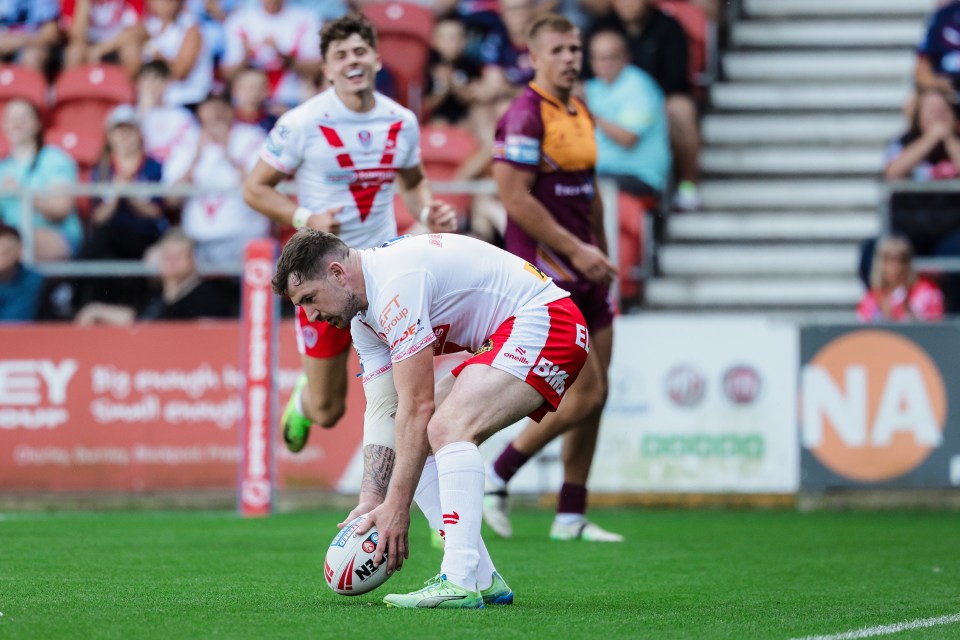Rugby player kicking a ball during a St Helens vs Huddersfield Giants match.