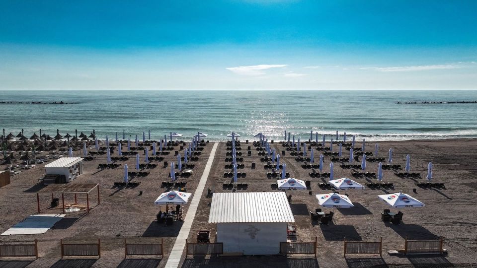 Aerial view of a beach with rows of umbrellas and lounge chairs.