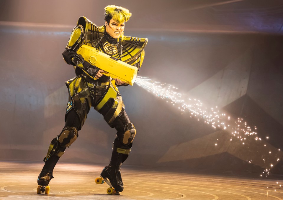 Roller skater in futuristic costume firing sparks from a weapon.