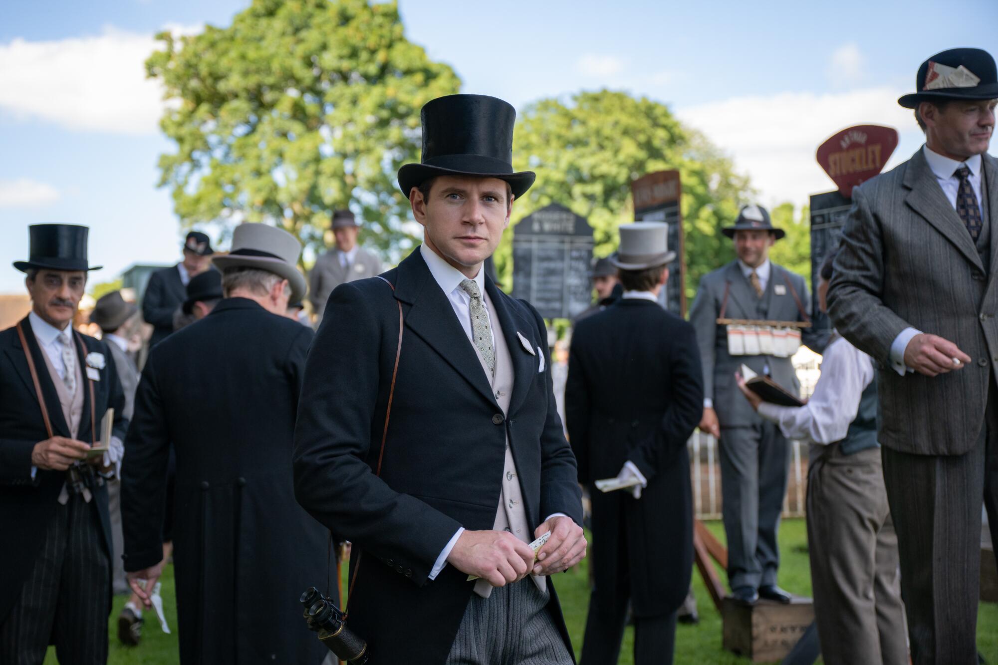 A man in a top hat attends an outdoor event.