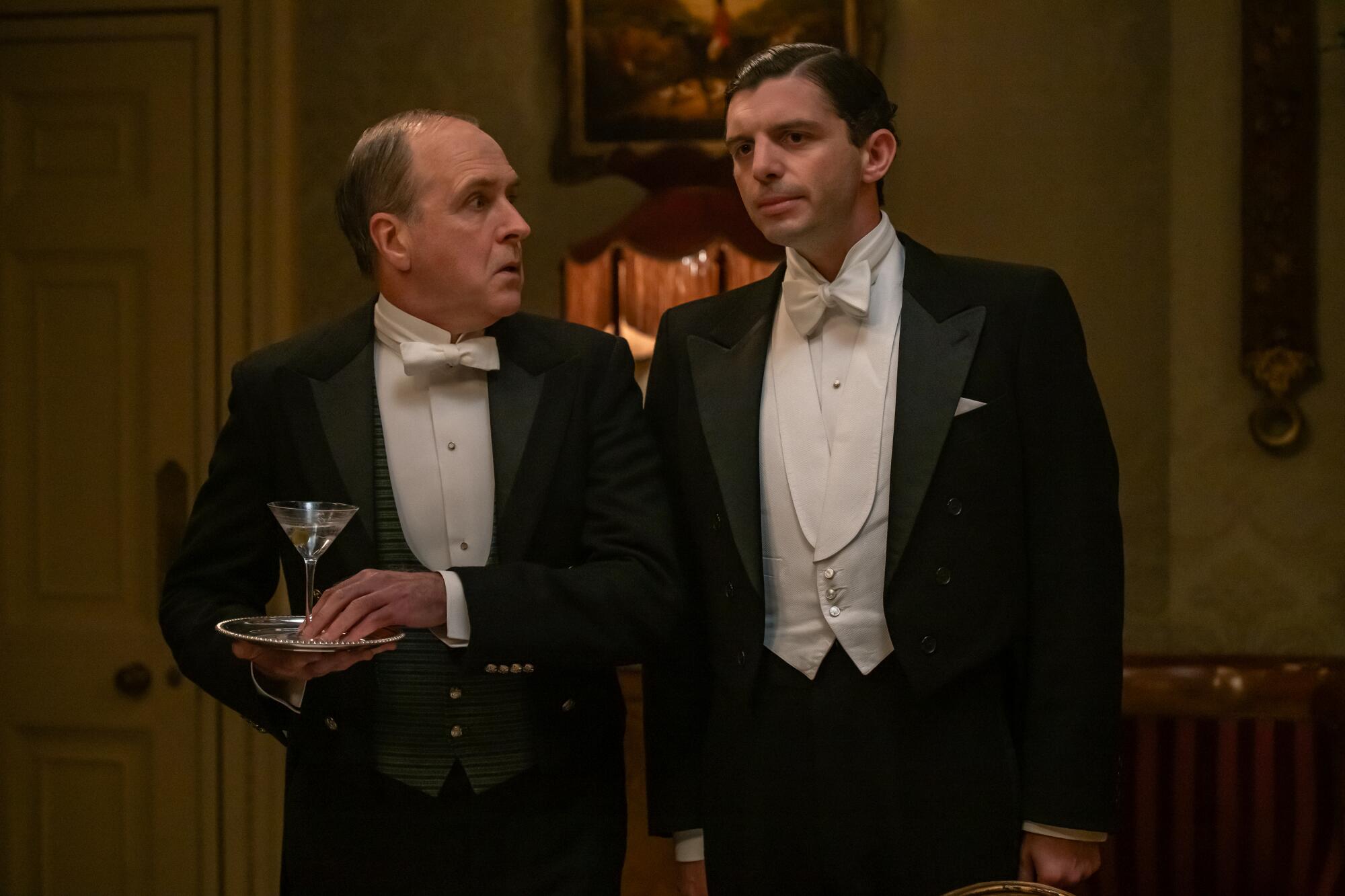 Two house staff members in formal dress serve at a party.
