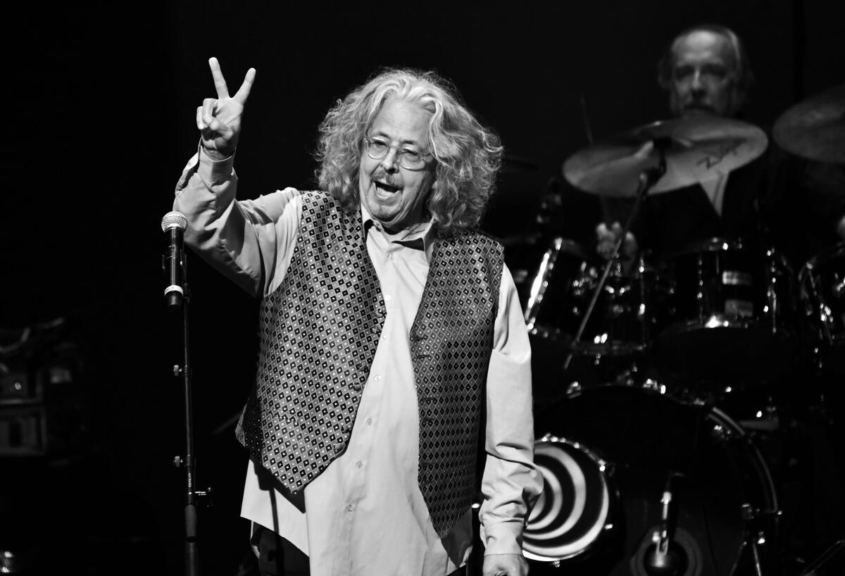 A rock singer onstage flashes a peace sign