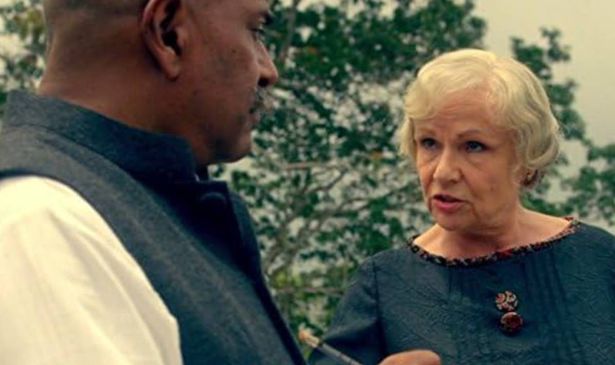 A woman with white hair talks to a man