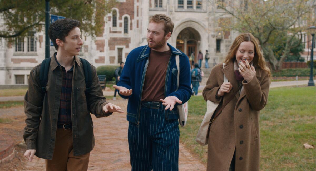 Two bantering men walk on a campus with a smiling woman.