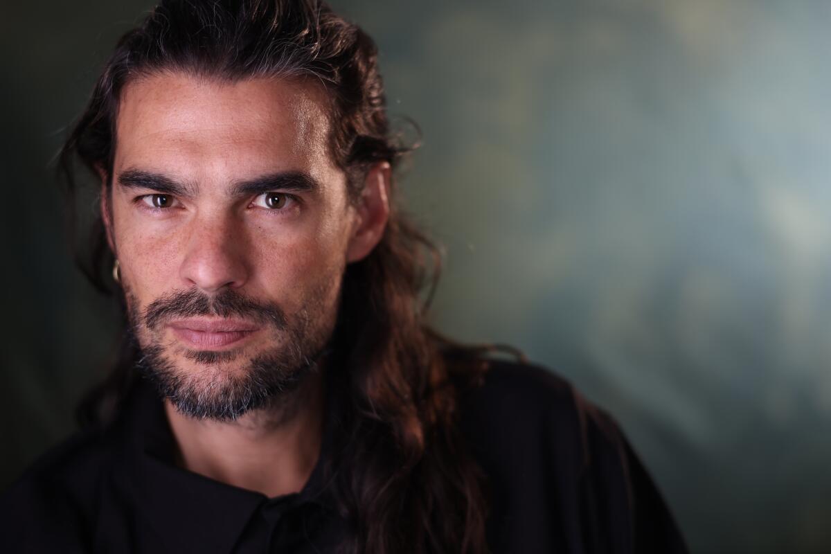 A bearded man stares into the lens.