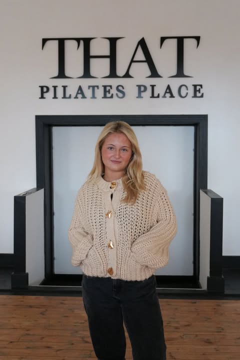 Woman in beige cardigan standing in front of That Pilates Place.