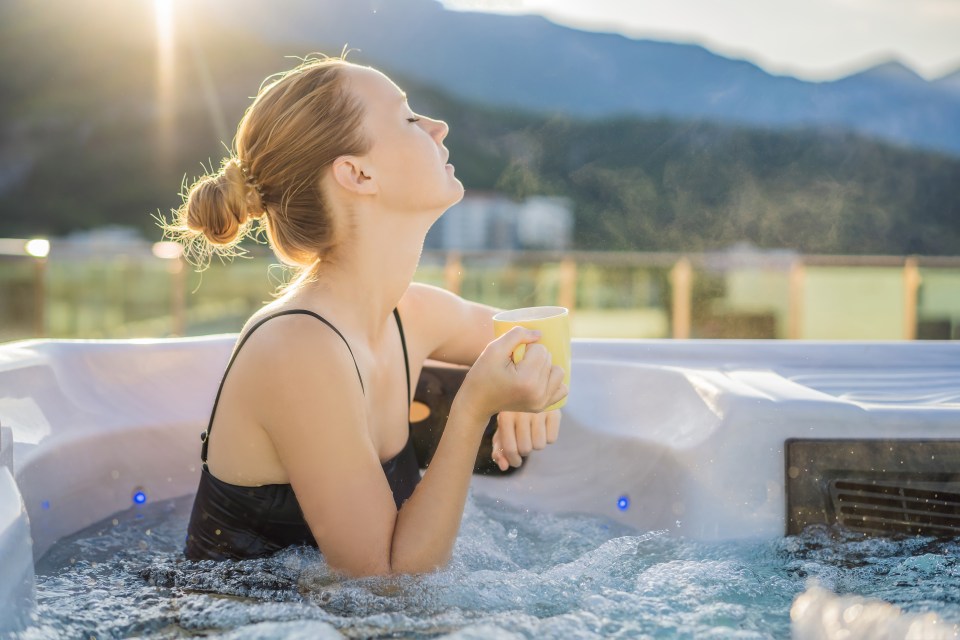 Woman relaxing in a hot tub with a mug.