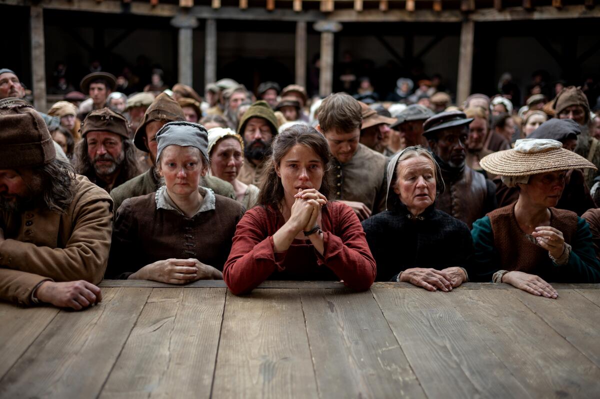 A woman in a red dress stands with other theatergoers in rapt attention.
