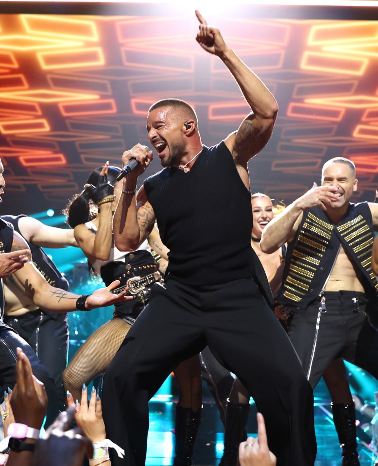 Ricky Martin performing on stage with backup dancers.