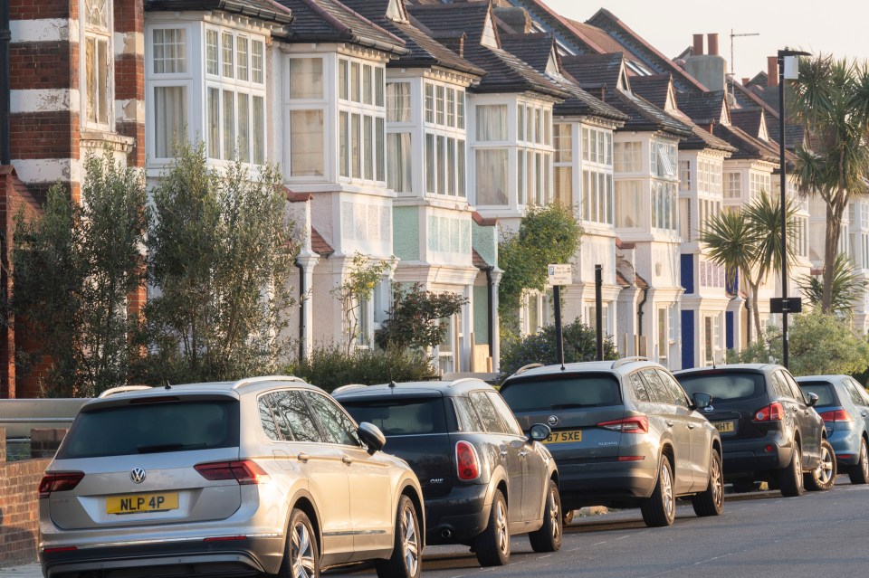 Row of terraced houses with cars parked on the street.