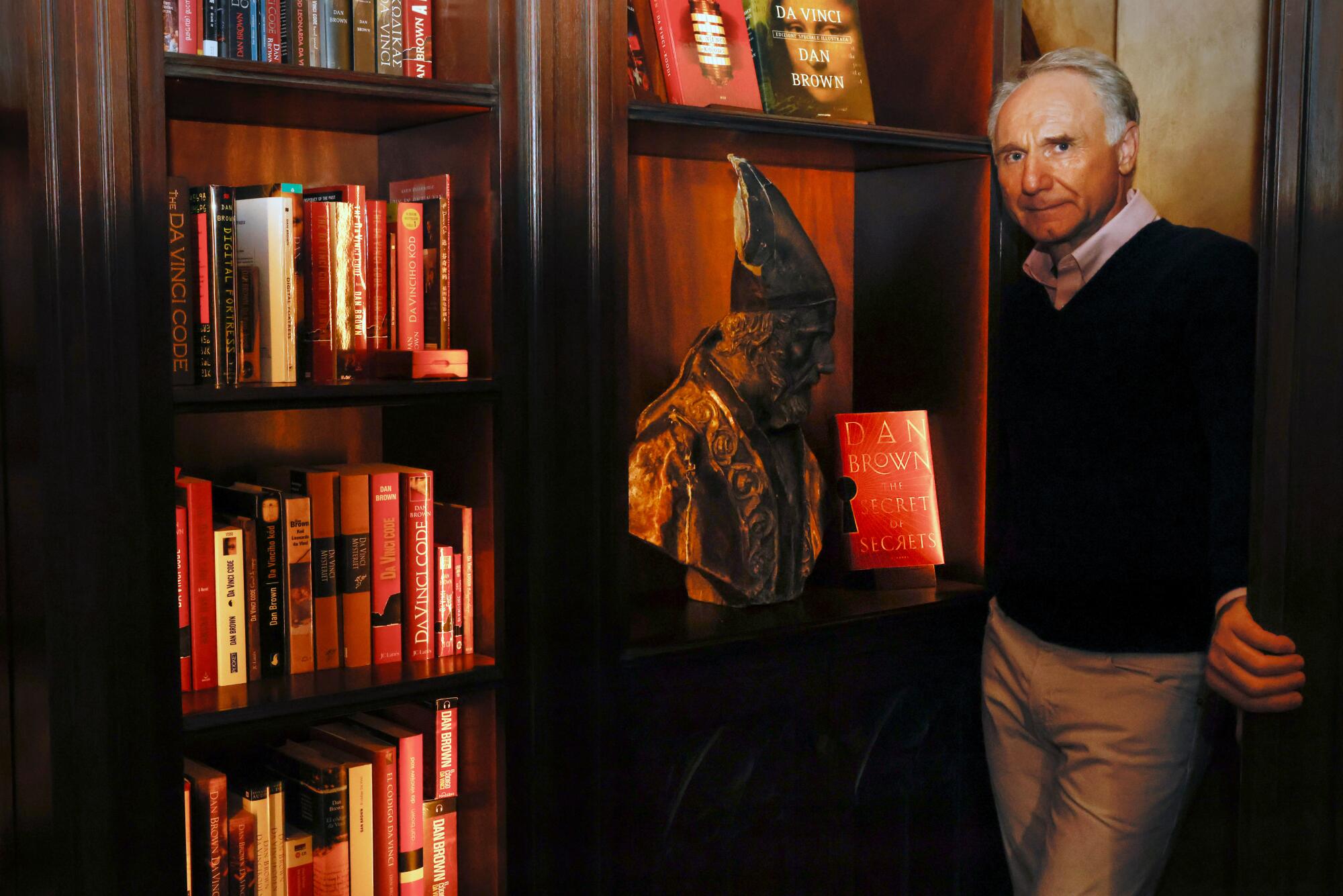 Dan Brown stands next to a bookcase at the door of his home library.