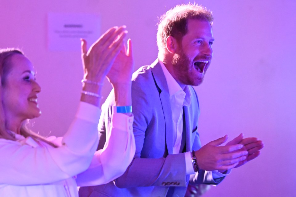 Prince Harry clapping enthusiastically at a live performance.