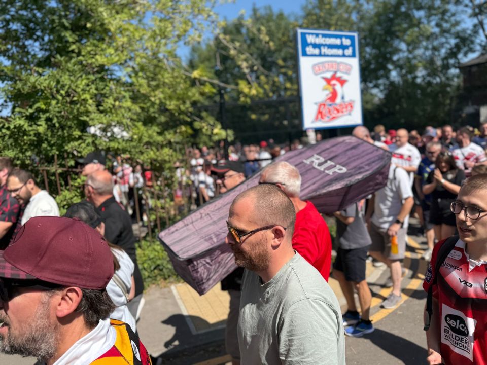 Salford rugby league fans protesting their owners, carrying a coffin-shaped sign.