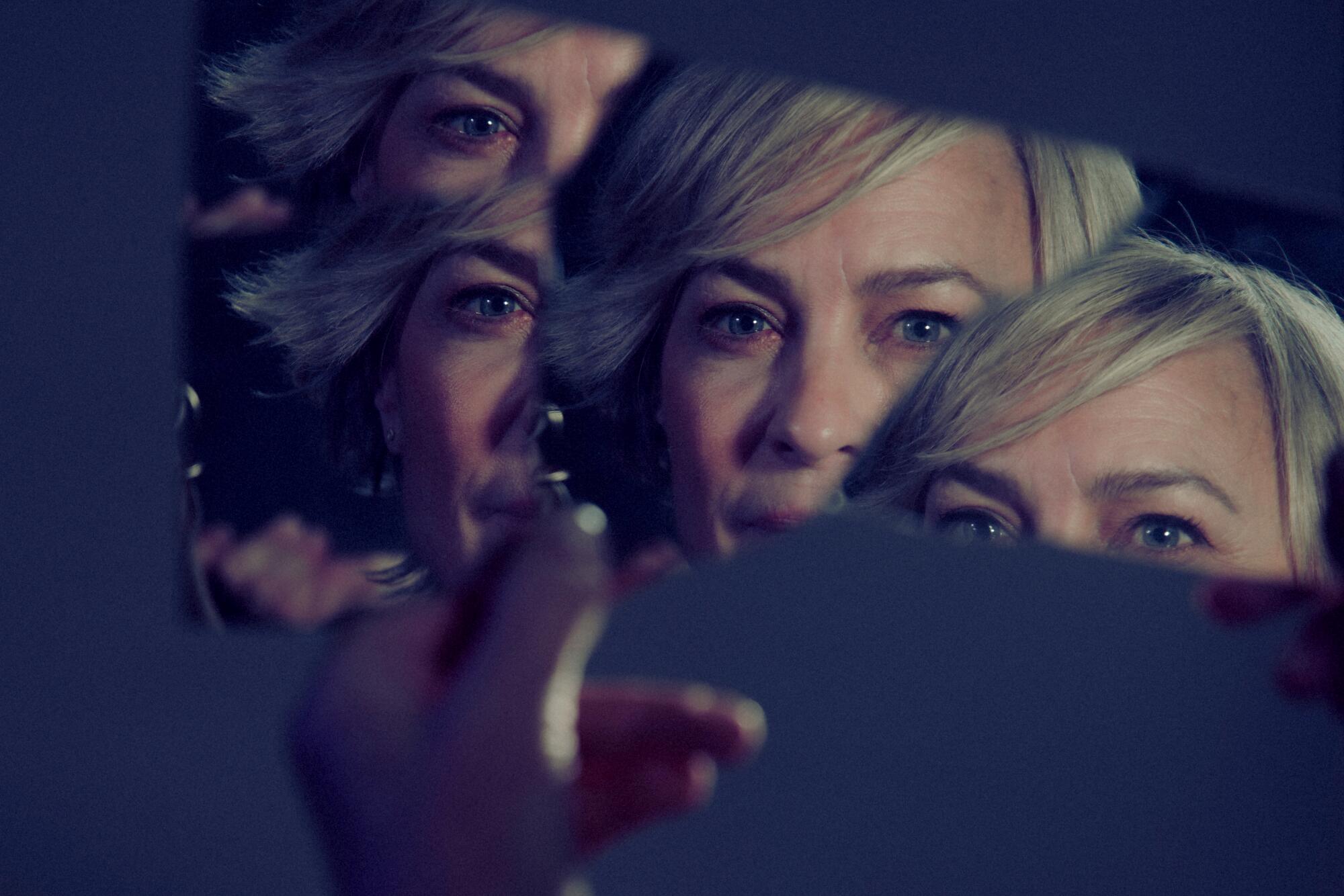 The face of a woman reflected on a shard of glass four times.