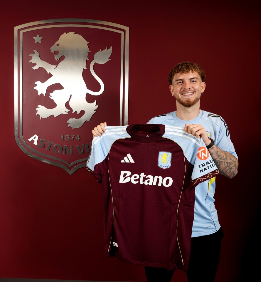 Harvey Elliott of Aston Villa holding up a team jersey.