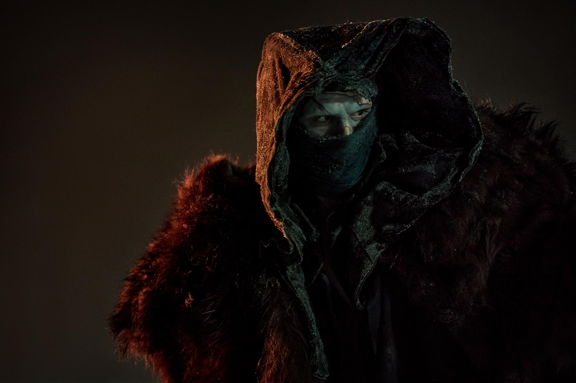 A creature looks out from under robes.