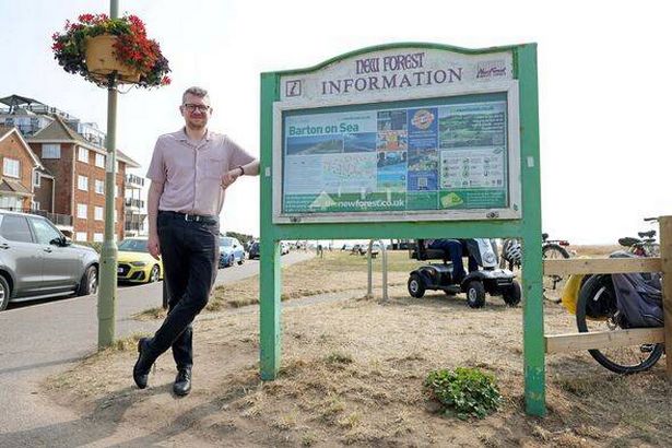 Adam Toms leans against sign in Barton