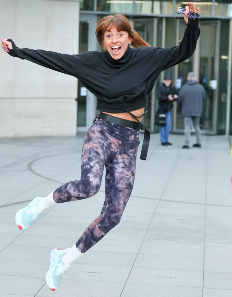Davina McCall leaping in the air, wearing leggings and a sports top.
