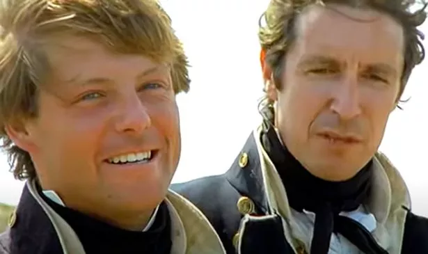 Two men stand together and smile 