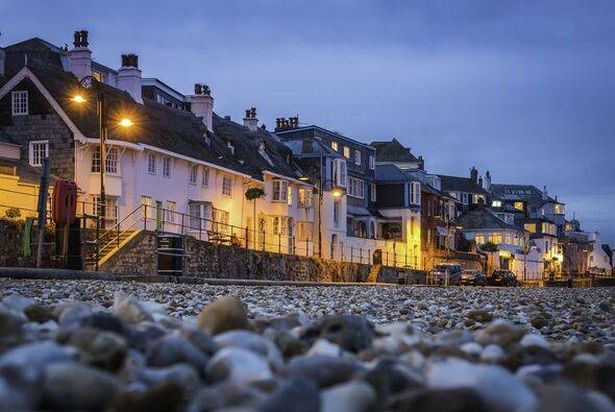 Seaside cottages overlooking pebble beach illuminated Lyme Regis Devon UK