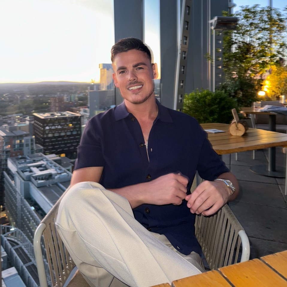 Man sitting at a rooftop restaurant overlooking a city.