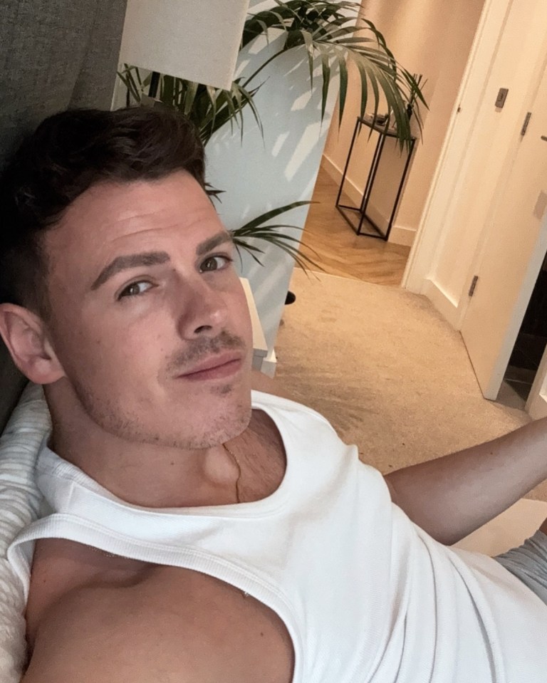 Man in white tank top relaxing indoors.