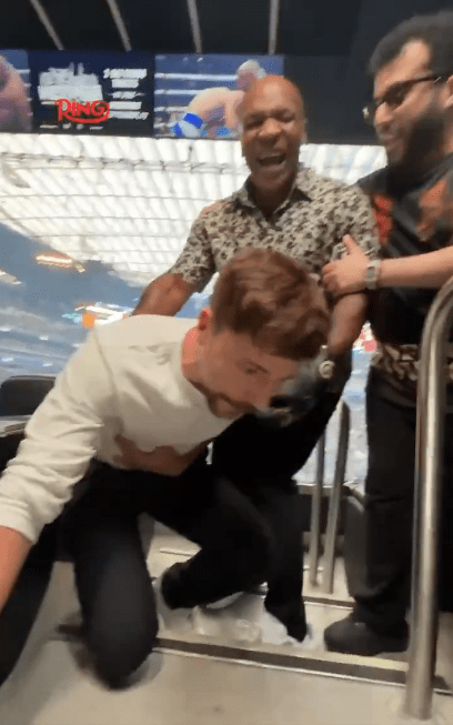 Man kneeling down while Mike Tyson laughs in the background.