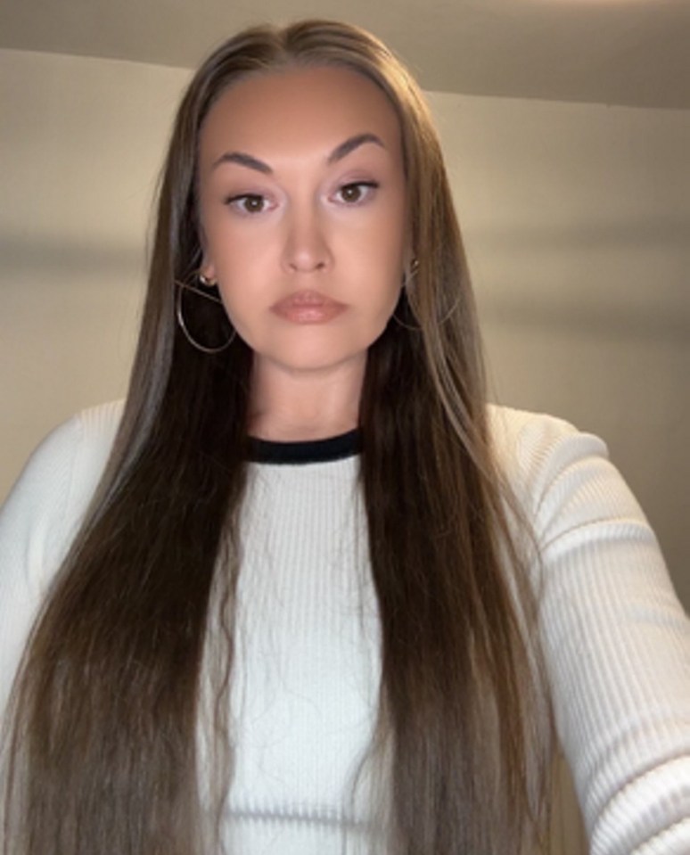 Woman with long brown hair wearing a white sweater.