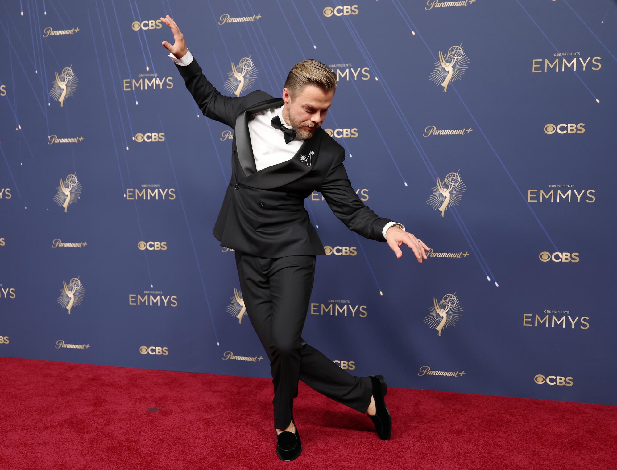 Derek Hough, in a tux, dances on the red carpet.