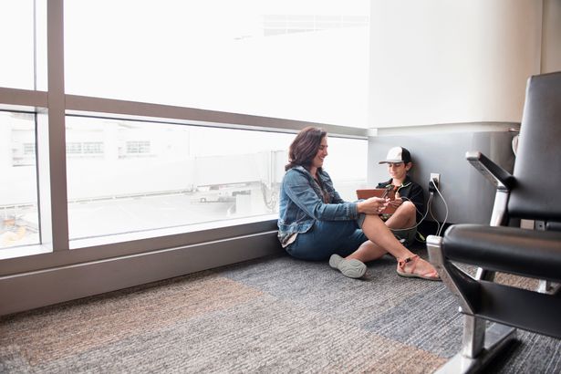 Image of woman and child sitting on the ground at airport