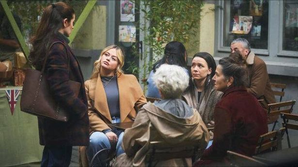 A group of women sat down staring up at another woman standing up