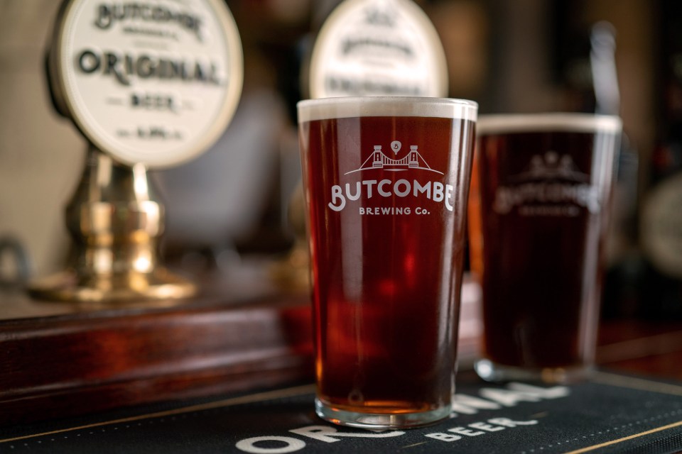 A pint glass of Butcombe Original Beer on a bar.