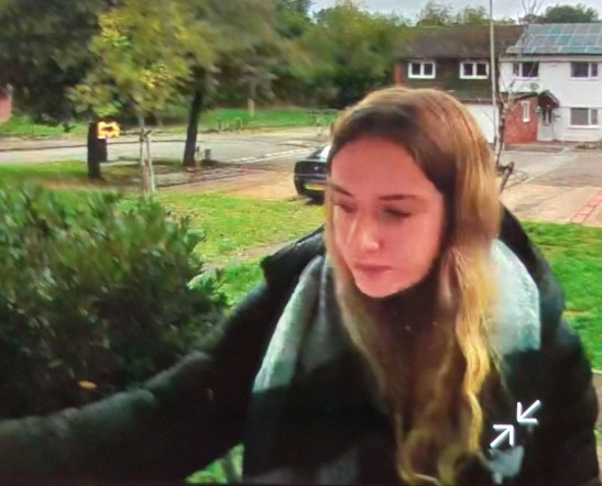 Lily Higgins, a young woman with long blonde hair, wearing a black coat and light blue scarf.
