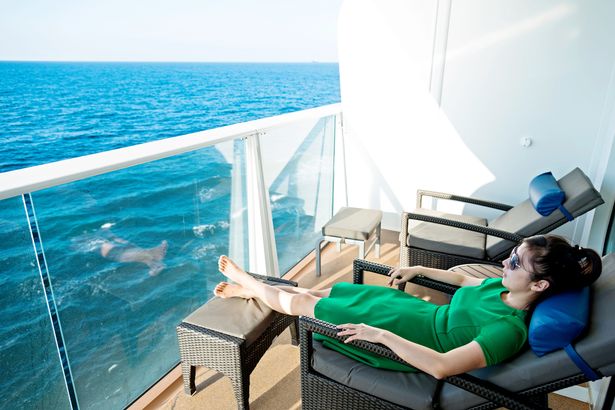 A young woman on a lounger on her cruise cabin balcony