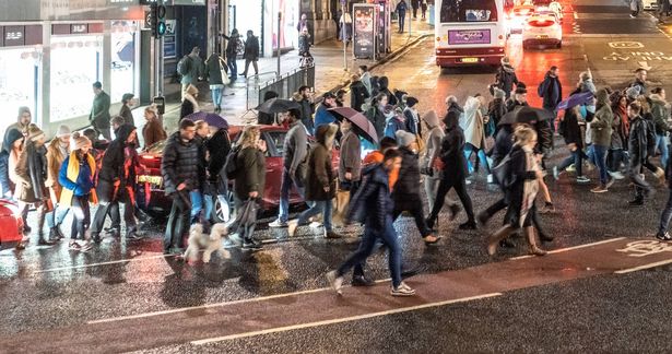 People crossing Hanover Street to continue on Princes Street in Edinburgh's city centre on a November evening.