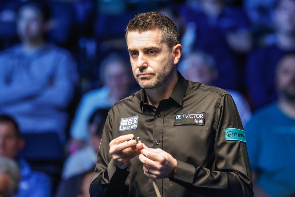 Mark Selby chalks his cue during a snooker match.