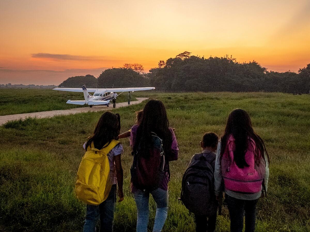 Four children stand beside each other while looking out at a sunset