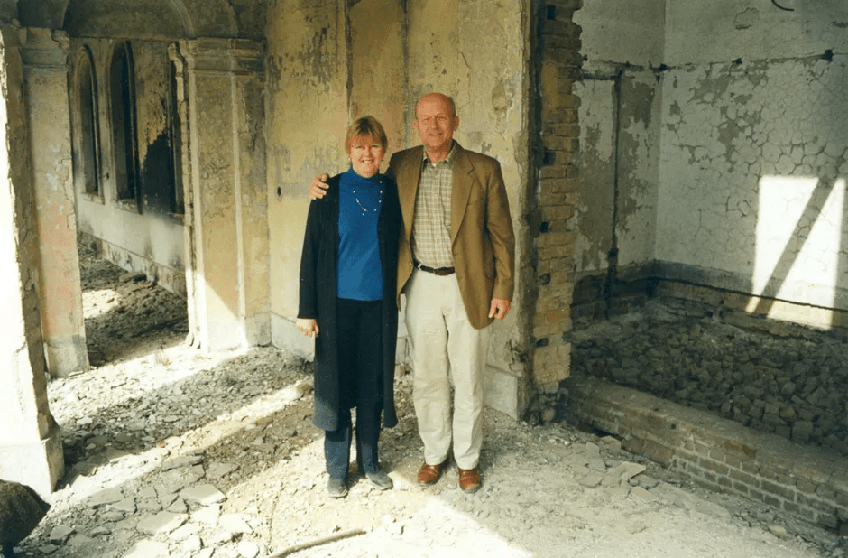 Two people standing in a dilapidated building.