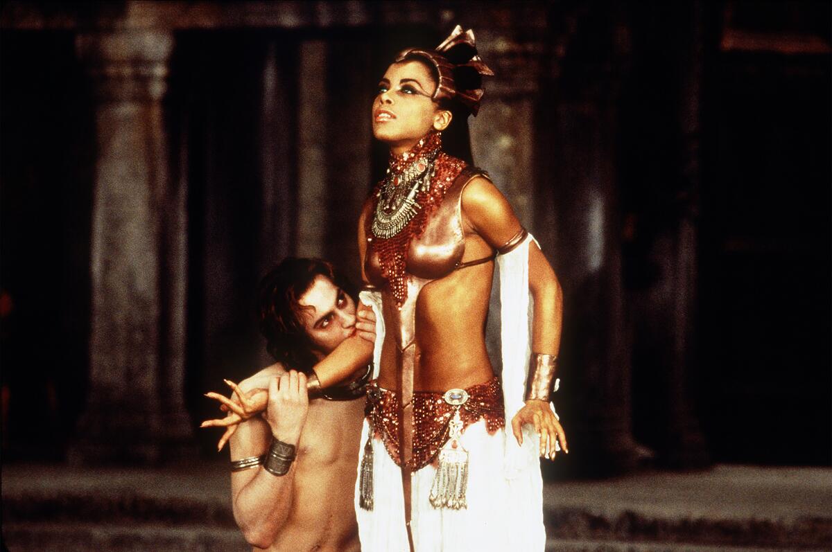 A kneeling man bites the arm of a woman.