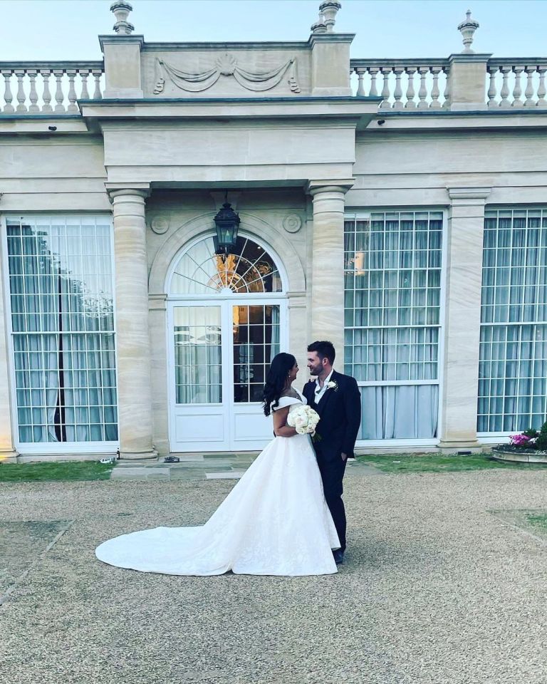 Shane Jr and Maddie Wahdan in wedding attire, standing outdoors in front of a grand building.