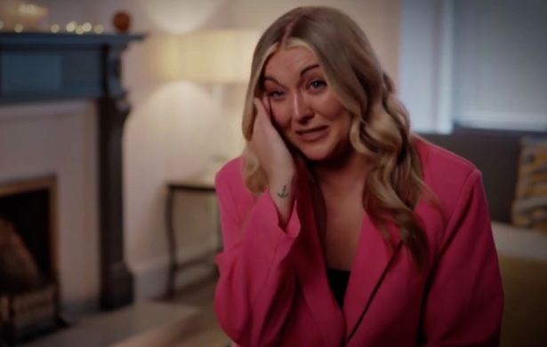 Married at First Sight UK star Sarah, in a pink jacket, wiping tears from her eyes with a living room scene behind her.