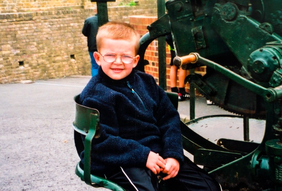 Andrew Gosden at age 5 sitting in a green metal structure.