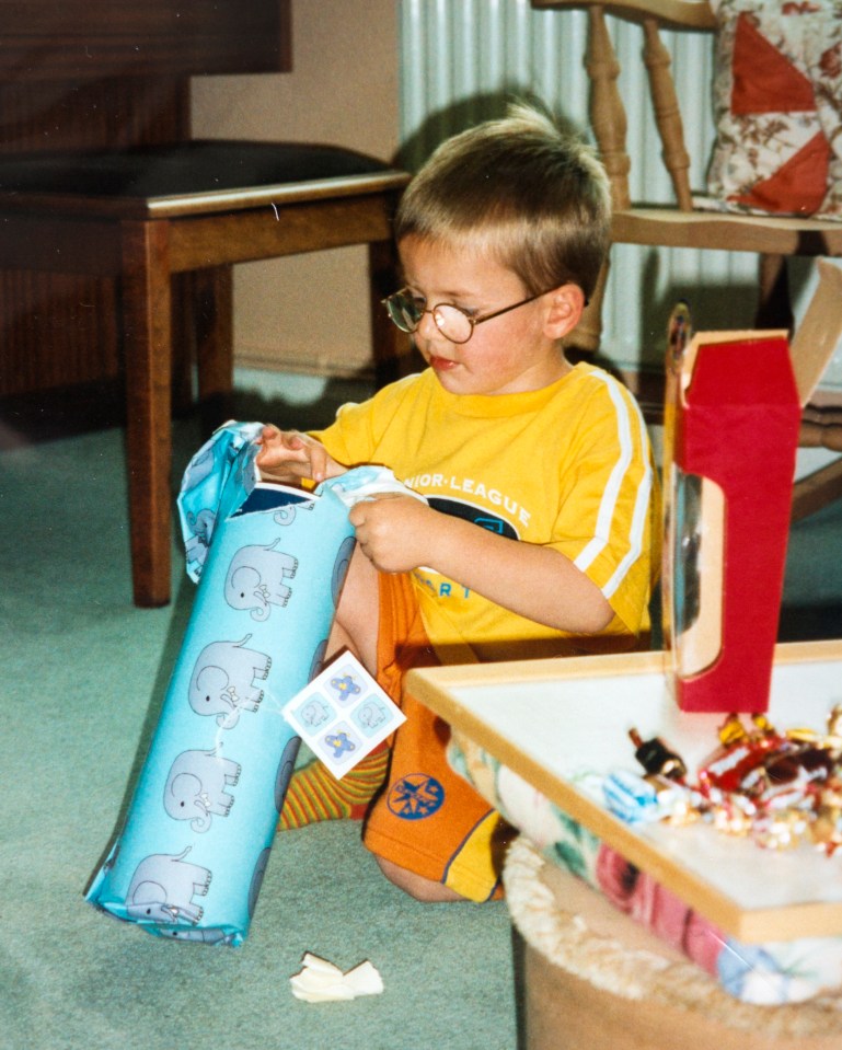 Andrew Gosden at age 5 unwrapping a gift.