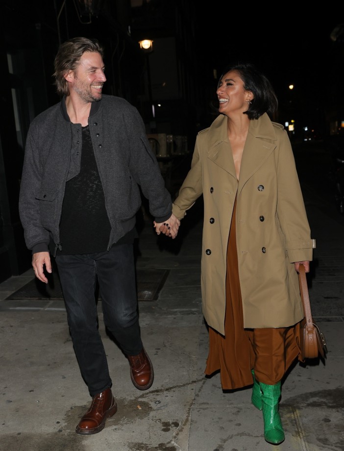 Anita Rani and new boyfriend hold hands and smile while walking.