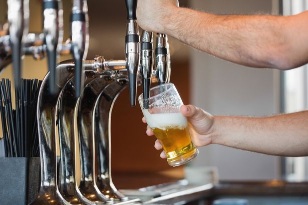Barmans arms pulling a pint of beer behind the bar