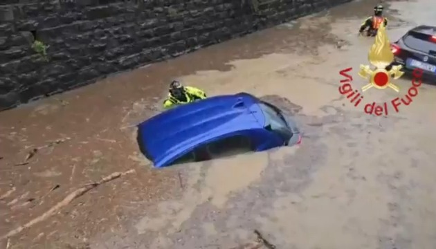 Firefighters rescue a driver stuck in a car in a flooded underpass in Turate, Como.