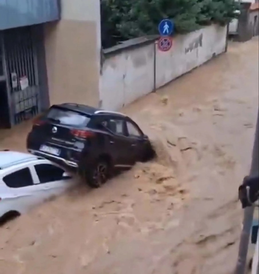 Two cars stuck in brown floodwaters in Meda, Italy, due to the overflowing Taro River.