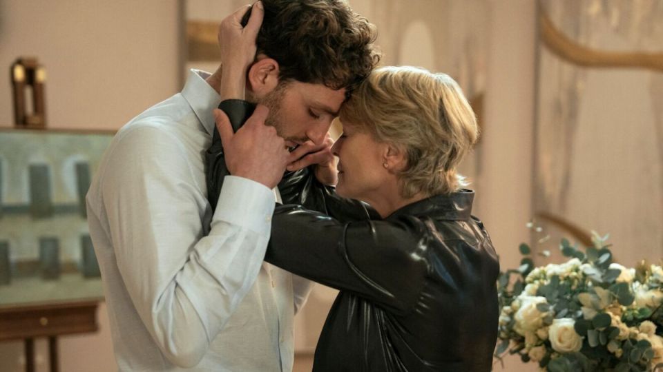 A man and woman with their foreheads touching, the woman in a black jacket and the man in a light blue shirt.