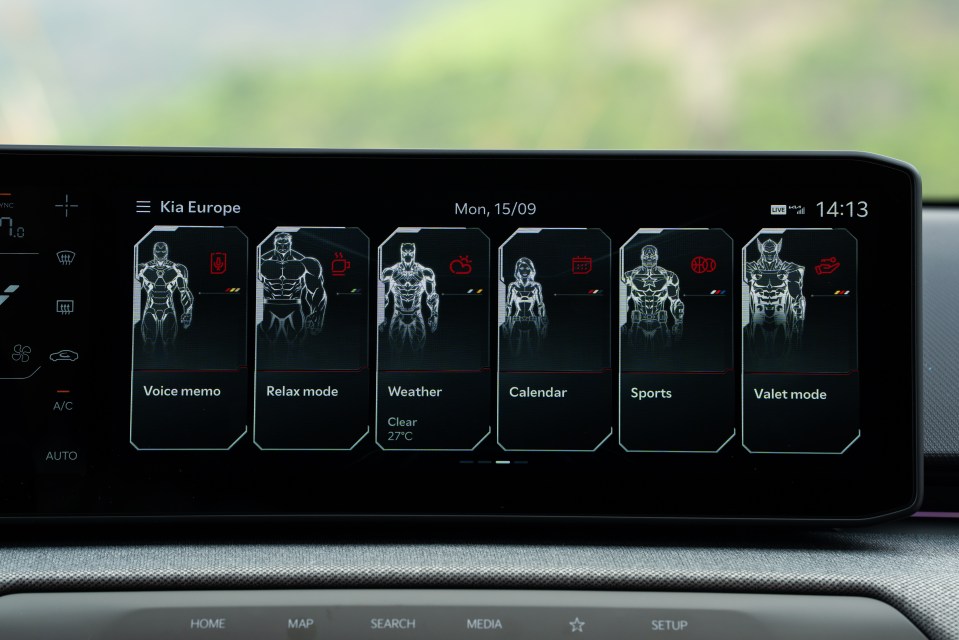 A car infotainment screen displaying the Kia Europe interface with options like Voice memo, Relax mode, Weather, Calendar, Sports, and Valet mode, each represented by a Marvel superhero illustration.